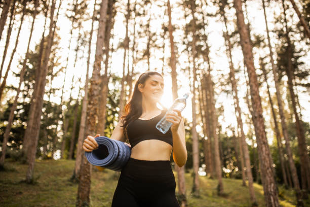 istock Sporty woman holding exercise mat, taking a break and drinking water on sunset 1328000973