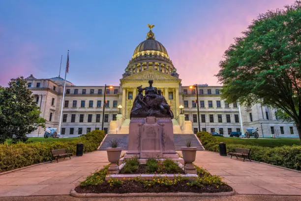 Mississippi State Capitol in Jackson, Mississippi, USA at twilight with the Monument to Women of the Confederacy dating from 1917.
