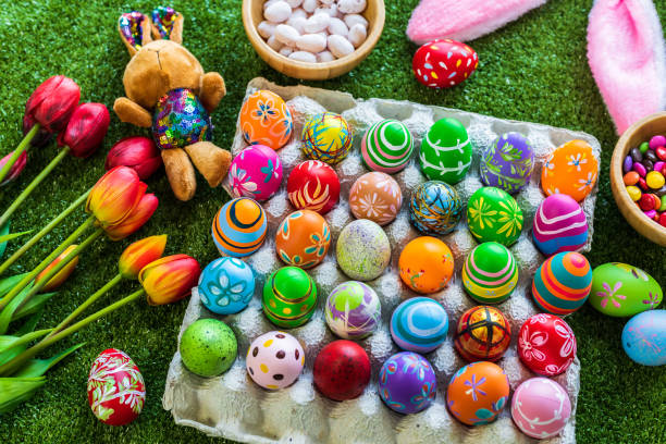 concepto de vacaciones de pascua, coloridos huevos de pascua en caja de huevos, huevos de pascua de cesta, cesta de caramelos, muñeca de conejo en fondo de hierba verde con espacio. - animal egg eggs basket yellow fotografías e imágenes de stock