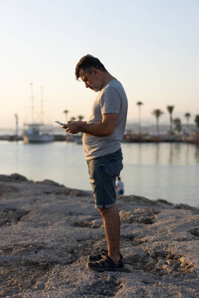istock Man driving drone with remote control in hands photographed by the sea 1328004314
