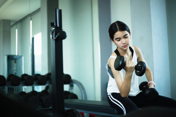 istock Young beautiful girl doing exercises with dumbbell in gym. 1328005603