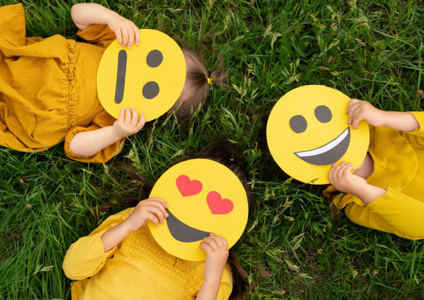 istock Three children lying on the grass are holding cardboard emoticons 1328007029