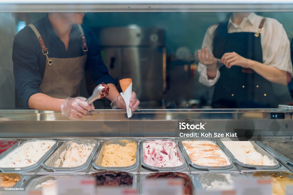 Gelato cafe staff serving a scoop of gelato Ice Cream Parlor Stock Photo