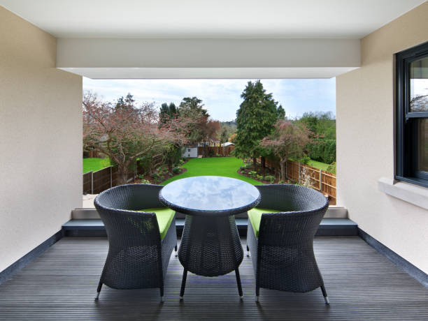 an unusual balcony outside of the bedroom of a luxury apartment with decking, a roof, a table to seat two for dining and a great view over the garden area