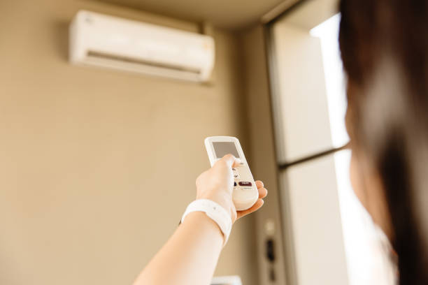 istock Closeup people using remote control adjust room temperature in home office pointing to Air conditioner in hot summer season. 1328011031