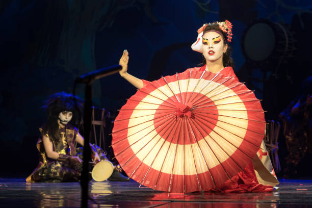 donna giapponese in kimono tradizionale con ombrello seduto sulle ginocchia nell'oscurità, un'altra nel backstage. kino kitsune fox è un personaggio delle leggende giapponesi. performance tradizionale giapponese. - kabuki foto e immagini stock