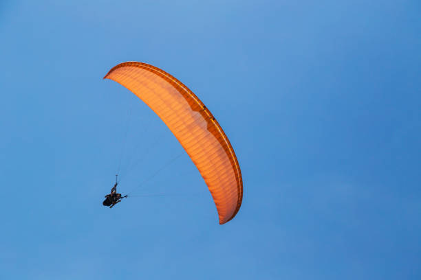 Myrtos Beach, Cephalonia island, Greece - July, 13 2019: Tandem orange paragliding against a blue sky, sunny day.