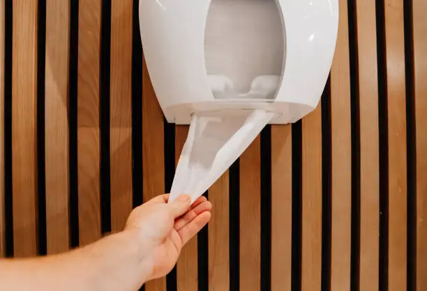 use of paper towels and toilet paper in a public toilet. convenience of disposable products for hygiene.