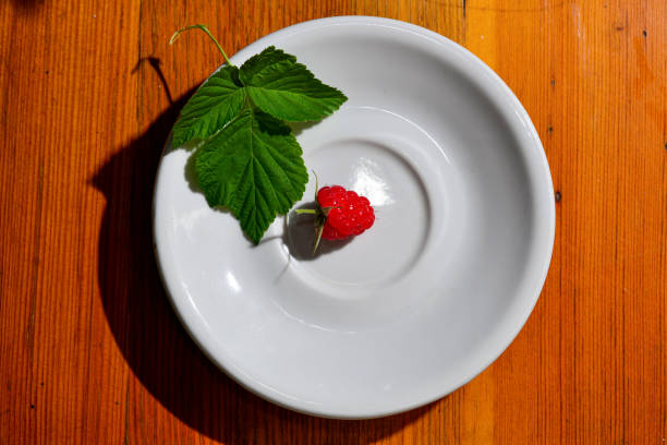 Red raspberry berry on a white saucer. Macro photo