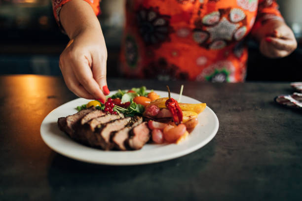 Mid-adult woman, using the current to arrange the plate with sirloin steak, and roasted vegetables on the side