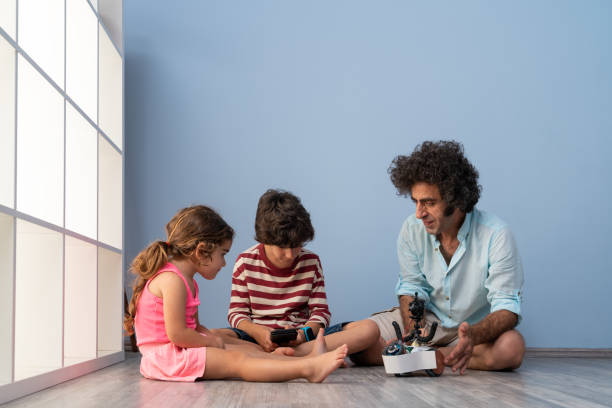 istock Father, Son And Daughter Playing With Robot 1328025522