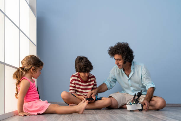 istock Father, Son And Daughter Playing With Robot 1328025529