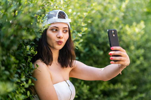 A young woman is taking selfies with a smart phone in nature.