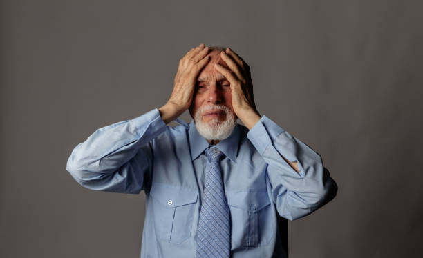 istock Old man in thoughts. Old man in blue is having a headache. 1328038116
