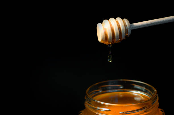 istock honey flows on a wooden spoon in a jar on a black background 1328041996