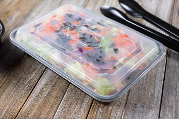 A view of a garden salad enclosed inside a plastic to-go box.