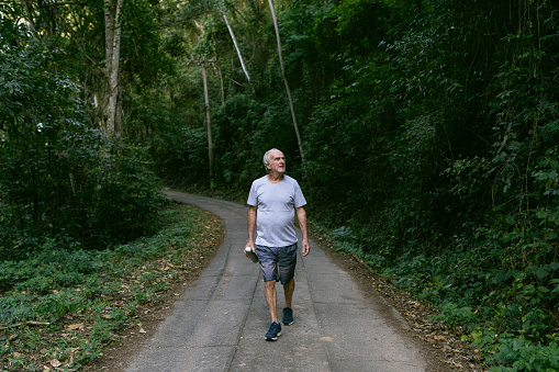 Active elderly man walking in nature reserve.