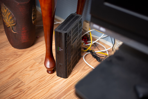 A view of a computer modem in the living room of a home.