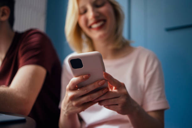 istock Smiling Young Woman Using her Mobile Phone While Sitting With Friends in a Coffee Shop 1328049279
