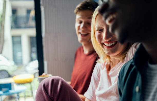 Cheerful multi ethnic group of friends sitting in cafe, drinking coffee and laughing together