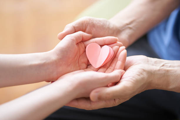 mani di caregiver e anziani con oggetti a forma di cuore - care foto e immagini stock