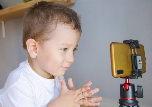 istock The boy looks at the phone on the tripod. 1328057723