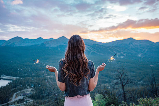 portrait artistique et rêveur d’une jeune femme debout tenant des feux d’artifice étincelants en été tout en regardant la magnifique montagne tenmile range dans le colorado près de breckenridge - tenmile range photos et images de collection