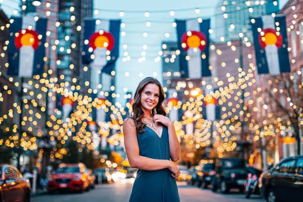 Portrait of a Beautiful, Fashionable Young Woman Standing Under Colorado Flags and String Lights on Larimer Square in Denver, Colorado at Dusk