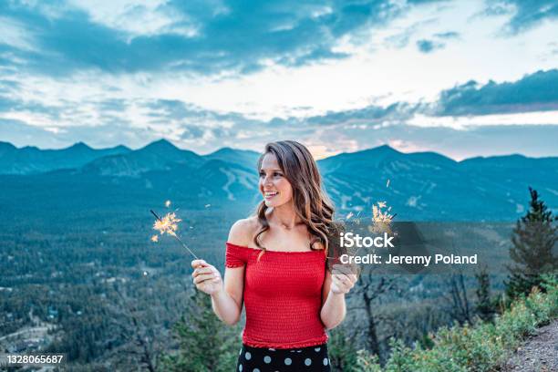 Artsy Dreamy Portrait Of A Young Woman Standing Holding Sparkler Fireworks To Celebrate In The Summer With Beautiful Tenmile Range Mountain View In The Background Stock Photo - Download Image Now