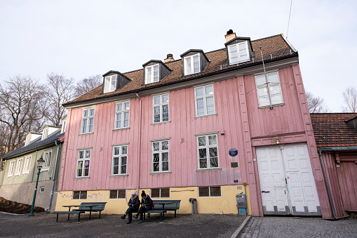 Oslo, Norway - February 24, 2021. Two senior women sitting on a chair in front of the historic house of Henrik Wergeland in Oslo, Norway