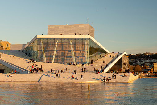 Oslo, Norway - February 23, 2021. Tourists enjoy their time at Opera House at sunset, Oslo, Norway