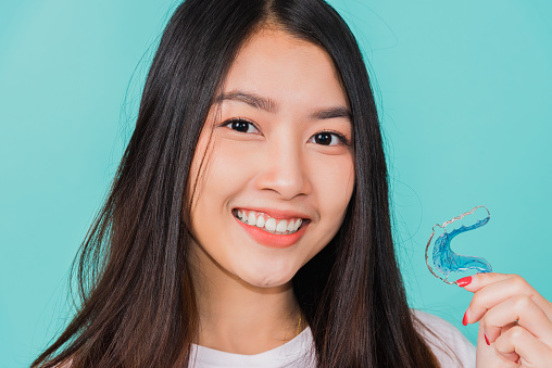 Portrait young Asian beautiful woman smiling holding silicone orthodontic retainers for teeth, Teeth retaining tools after removable braces, Orthodontics dental healthy care concept