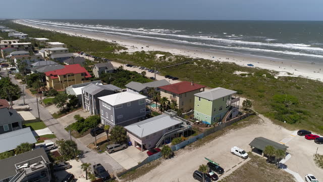 Aerial view of the residential suburban area of Saint Augustine, Florida, spreaded along the sandy beach of Atlantic Ocean, behind the narrow dune covered with shrubs and plants.