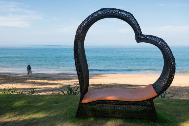 istock Heart shaped chair with blur couple on beach 1328074888