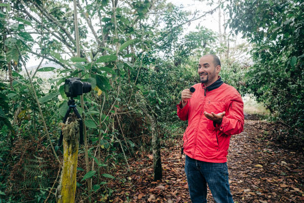 Man talking into a microphone while recording in a place surrounded by nature stock photo