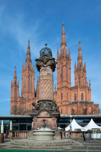 market church in Wiesbaden with historic market pillar from 19th century with fountain under blue sky
