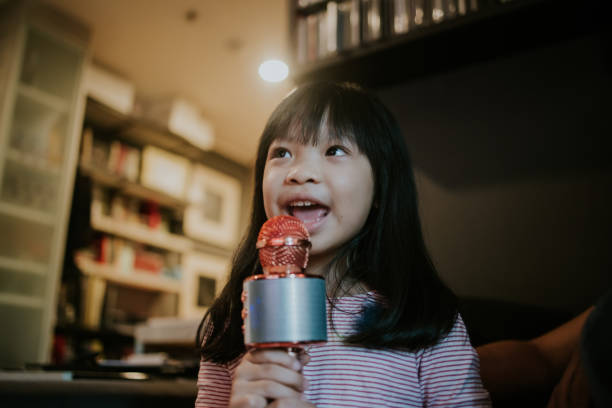 thai little girl sogna di essere una cantante e diventare una star nella sua immaginazione in salotto - foto d'archivio - toddler music asian ethnicity child foto e immagini stock