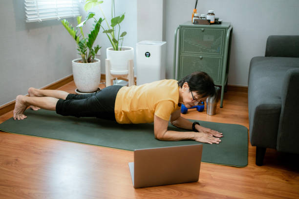 istock Asian senior woman following tutorial online and exercise at home during isolation for Covid - 19 . 1328085591