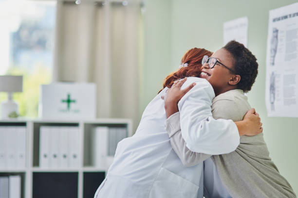 disparo de una joven abrazando a su médico durante una consulta - abrazarse fotografías e imágenes de stock