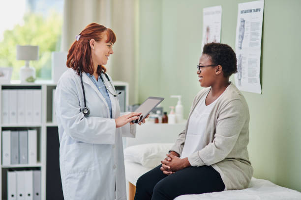 scatto di un medico che usa un tablet digitale durante una consultazione con una donna - visita foto e immagini stock