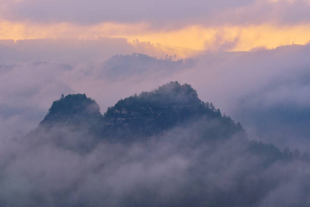 Morning after heavy rainy night. Misty clouds in valley. Foggy forest during sunrise, Saxon Switzerland, Germany.