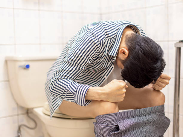 Young man feels uncomfortable in his stomach and is constipated in the toilet Young man feels uncomfortable in his stomach and is constipated in the toilet Constipation stock pictures, royalty-free photos & images