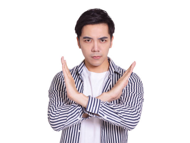 Young and handsome man, expressing rejection gesture, bigger than X gesture on his chest.Isolated on white background. stock photo