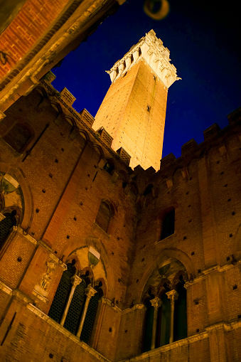 A suggestive night view of the Palazzo Pubblico (Town Hall) and the majestic Torre del Mangia (Mangia's Tower) in the famous Piazza del Campo, in the heart of the medieval city of Siena, in central Italy. Built starting in 1290, the Palazzo Pubblico was the seat of the Council of Nine and the executive power of the medieval city. Currently it is still the seat of the municipal government of the Tuscan city. Siena is one of the most beautiful Italian cities of art, in the heart of the Tuscan hills, in central Italy, famous for its immense artistic and historical heritage and for the Palio, where the seventeen districts of the city compete every year in Piazza del Campo in one of the oldest horse racing in the world. Since 1995 the historic center of Siena has been declared a World Heritage Site by UNESCO. Image in high definition format.