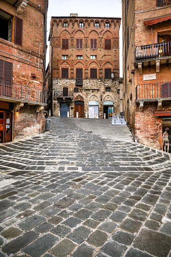A suggestive view of a lovely corner in Piazza del Campo square, the medieval heart of Siena with its characteristic shell shape. Siena is one of the most beautiful Italian cities of art, in the heart of the Tuscan hills, in central Italy, famous for its immense artistic and historical heritage and for the Palio, where the seventeen districts of the city compete every year in Piazza del Campo in one of the oldest horse racing in the world. Since 1995 the historic center of Siena has been declared a World Heritage Site by UNESCO. Image in high definition format.