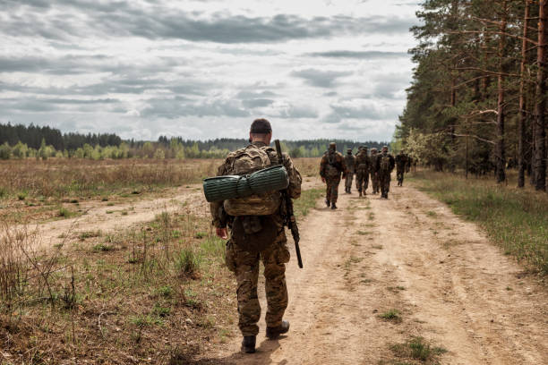 roup of soldiers in camouflage military uniforms with weapon combs through area Adult war team games with weapons, airsoft or strikeball, in forest. Group of soldiers in camouflage military uniforms with weapon combs through area. Military unit in woodland uniform with gun army stock pictures, royalty-free photos & images