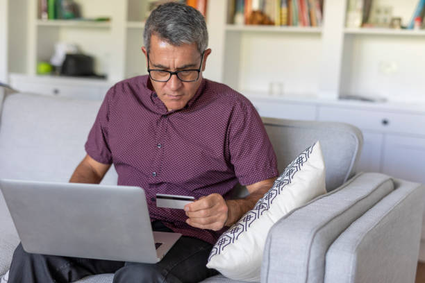 istock Mature Man Entering Credit Card Details into a Computer 1328103521