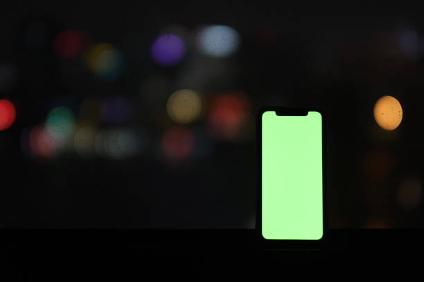 close up green screen mobile phone in dark with colorful bokeh