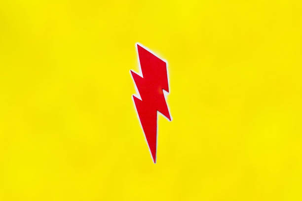 Red lightning arrow made of cardboard on a yellow background stock photo