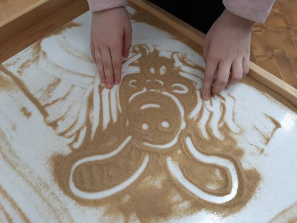 A girl draws a bunny on a light table. Drawing sand